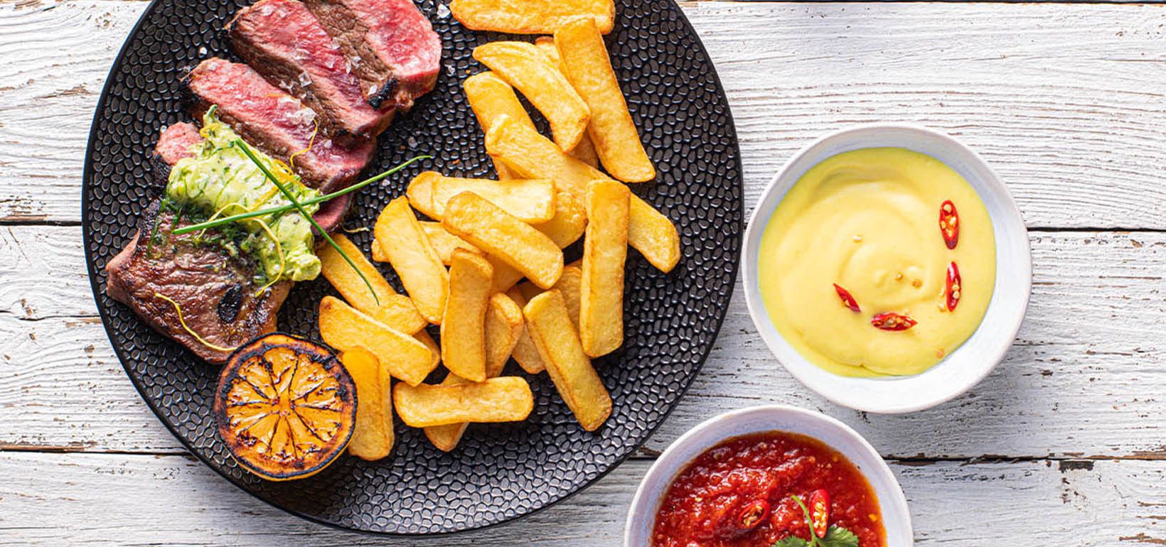 Grilēts antrekots, pasniegts ar Steak Fries kartupeļiem frī un mājās gatavotām mērcēm